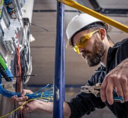 A,male,electrician,works,in,a,switchboard,with,an,electrical